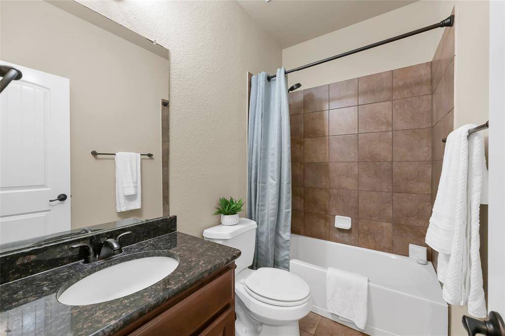 Secondary bathroom holds a shower-tub combo and a large sink counter