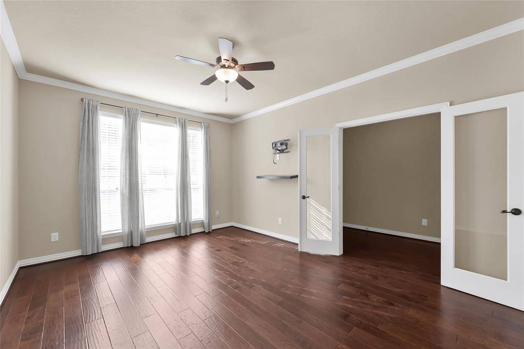 the expansive home office features hardwood floors, a built in ceiling fan, and is accessible from the entryway.