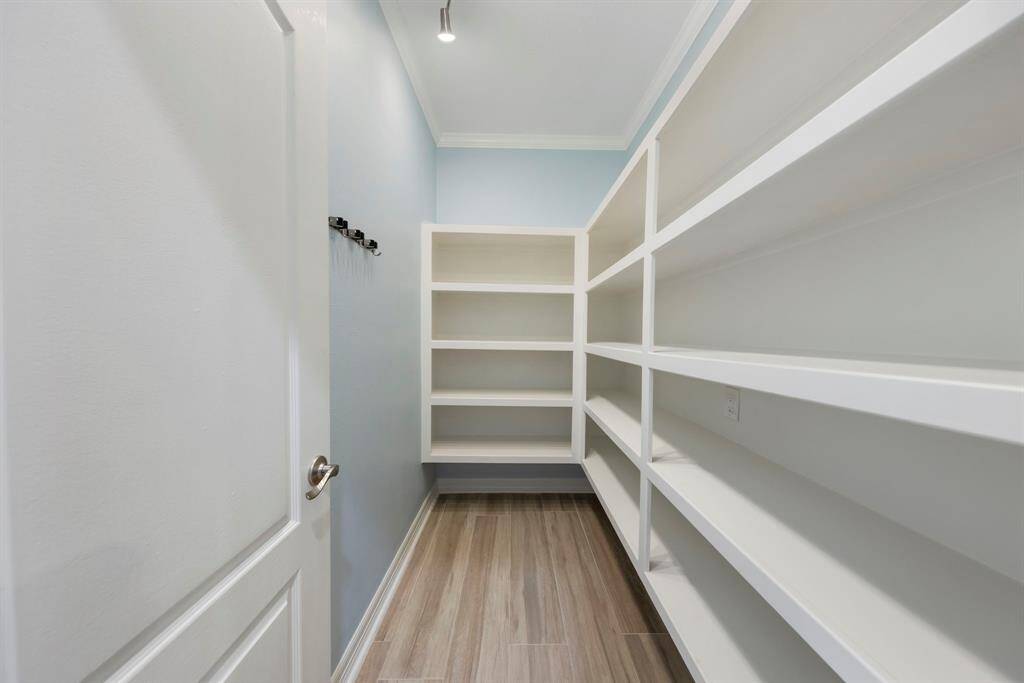 A spacious walk-in pantry with shelving provides ample storage for all your culinary essentials, keeping everything organized and within easy reach.