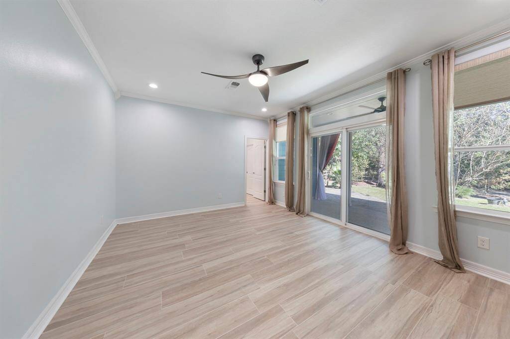 The primary bedroom boasts new windows and a sliding glass door that opens to the back covered patio, complemented by a stylish fan for added comfort and elegance.