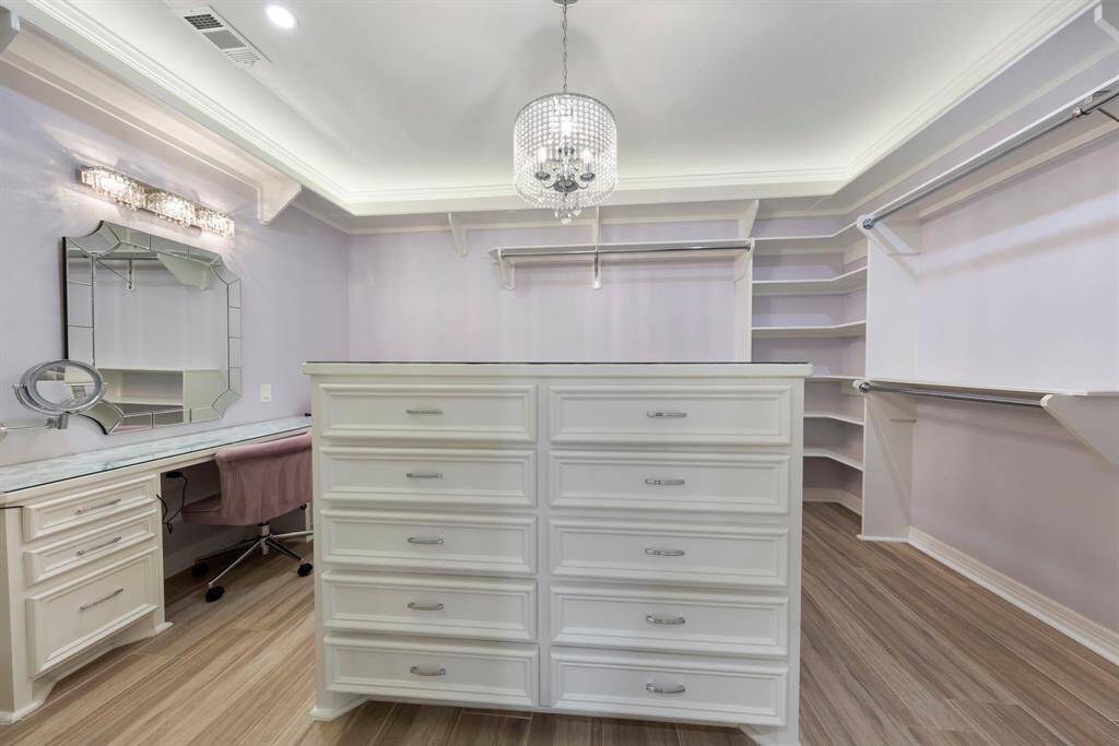 One of the two custom walk-in closets features a stylish island for additional storage and a dedicated vanity area.
