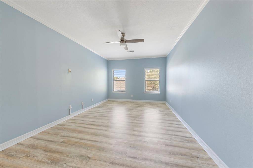 The second of three upstairs bedrooms showcases fresh paint, LVP flooring, a new ceiling fan, and bright windows.