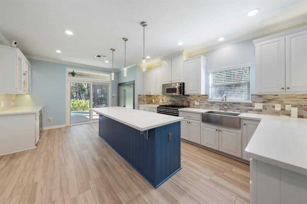 The kitchen is equipped with stainless steel appliances, enhanced by recessed lighting and a stylish tile backsplash.
