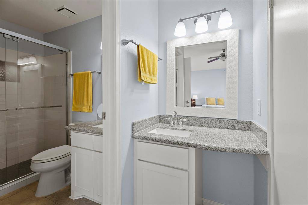 The primary bedroom has its own vanity and sink, and it enjoys direct access to the bathroom.