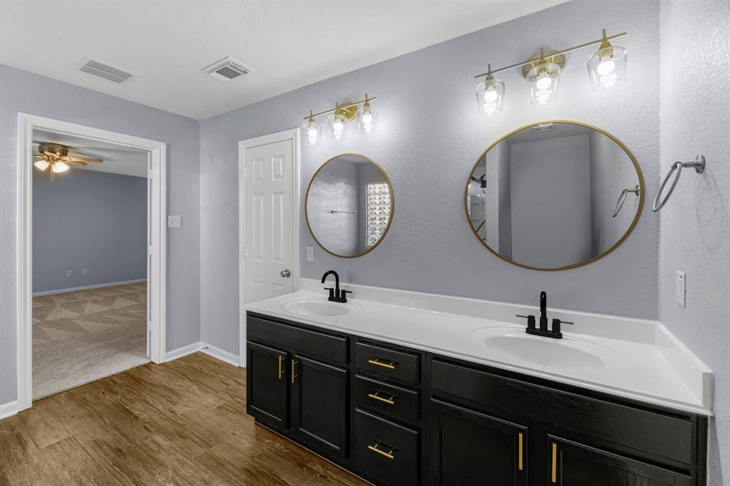 Sleek black fixtures, dual sinks, round mirrors, and abundant storage.