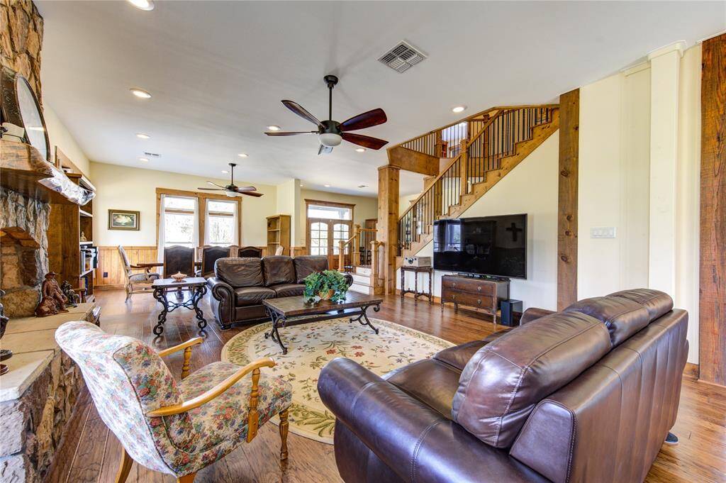 The open layout includes a dining area, wooden staircase, and high ceilings with ceiling fans, creating a warm and inviting atmosphere.