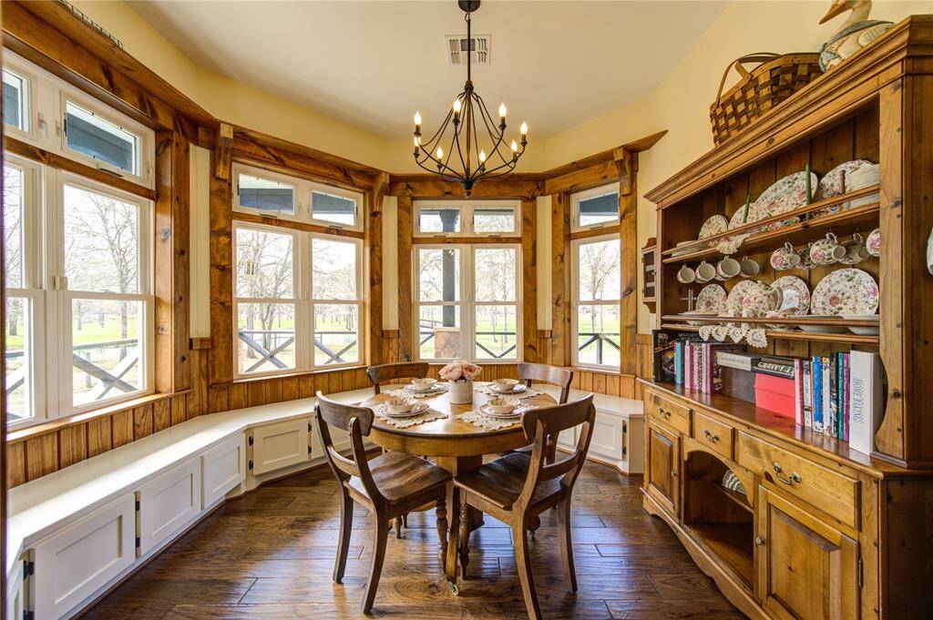 This inviting breakfast room features large bay windows, offering abundant natural light and scenic views. The space includes built-in seating with storage and a charming chandelier overhead. Perfect for intimate meals and gatherings.