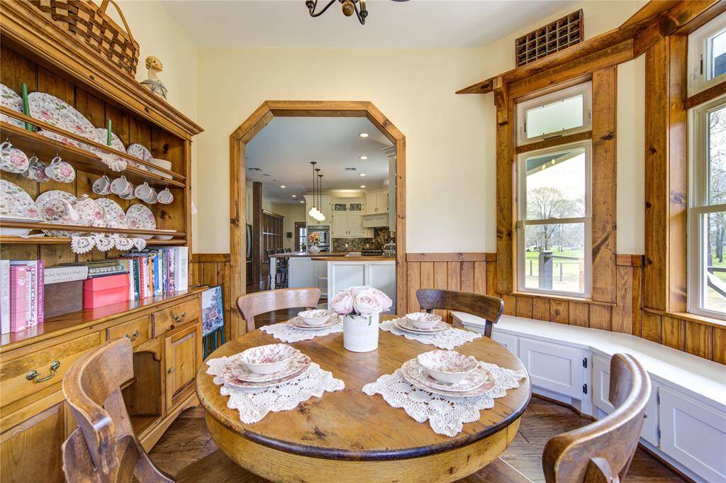 This dining area features natural wood accents and large windows to create a warm, comfortable atmosphere with views of the lush greenery outside.