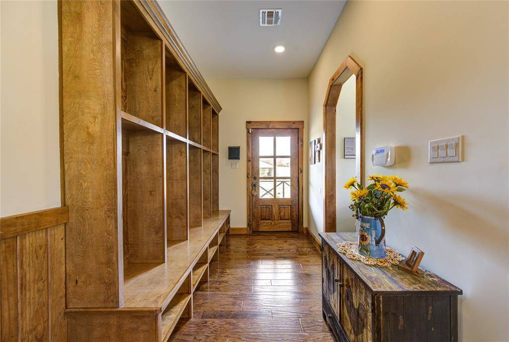 This welcoming side entryway features warm wood tones with built-in shelving.  This MUD room space has power outlets and charging stations in each cubby. Perfect for all the things!