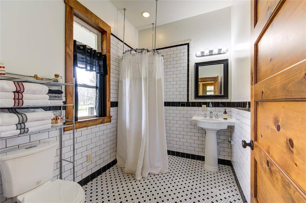 The guest en suite bathroom ADA compliant with wheel-in access if needed. The black and white accents and large window add to the charm along with large window bringing in natural light.
