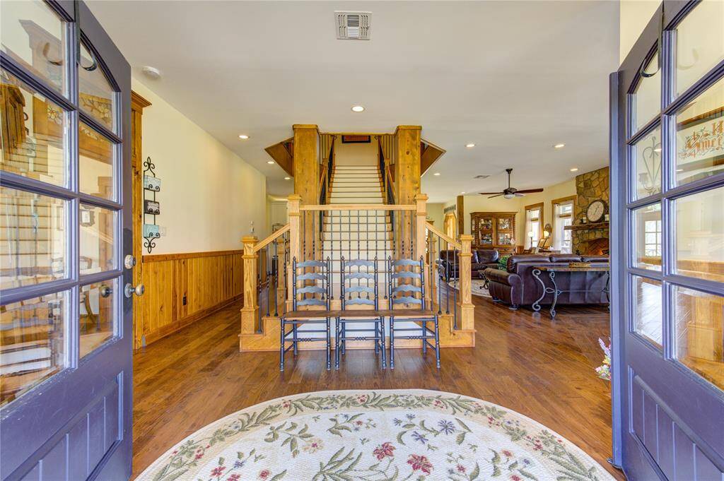 Welcome to this charming rustic home featuring a warm wooden staircase and flooring. The open entryway leads to a cozy living area with a stone fireplace and ample natural light. The space blends traditional and comfortable elements, ideal for family living.
