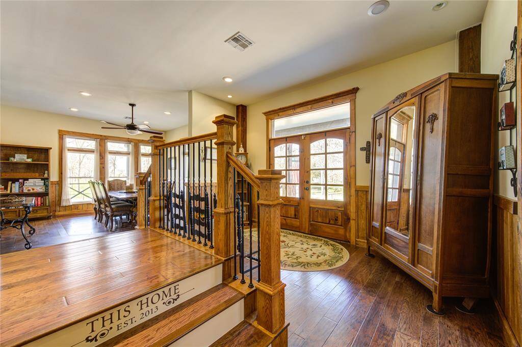 This inviting home features a warm, open space with rich wood flooring and trim. The entryway has large windows and glass doors, allowing natural light to fill the room.
