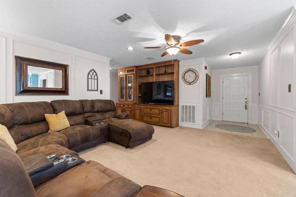 Built-in entertainment center and beautiful picture frame decorated panel walls in this spacious living room.