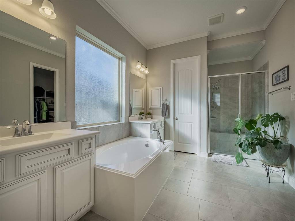 primary bath has 2 person glass door shower, soaking tub, double vanities and frosted window