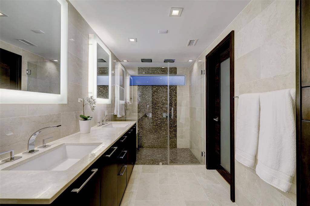 The primary bath is wrapped in marble tile and countertops and has two sinks and two shower heads.