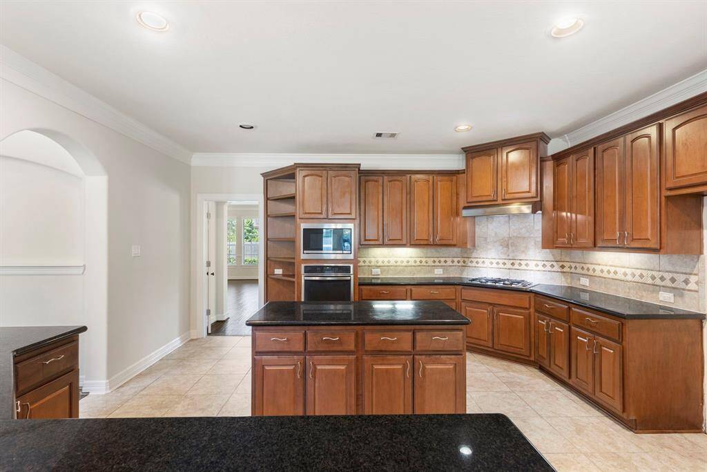 Island kitchen with tons of granite countertops, stainless steel appliances and under cabinet lighting.