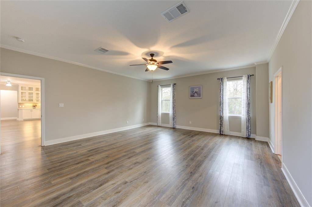 Located just off the kitchen, the expansive primary bedroom offers both convenience and tranquility.  Bathed in natural light, this private retreat provides breathtaking views of the heavily wooded surroundings, allowing you to immerse yourself in the beauty of nature from the comfort of your own space.