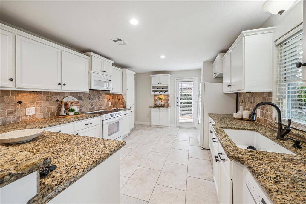 This immaculate kitchen is ready for you to show off your culinary skills. Find gorgeous granite countertops, tile backsplash with under-cabinet lighting, crisp white cabinetry & appliances, a large pantry and more.
