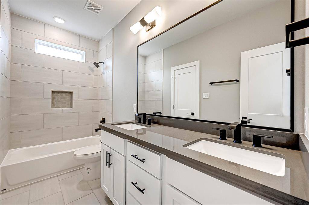 The 5x10 SF bath shared by bedroom two and three has a quartz counter, double undermount sinks, Moen hardware, and tub/shower combo with tile surround.
