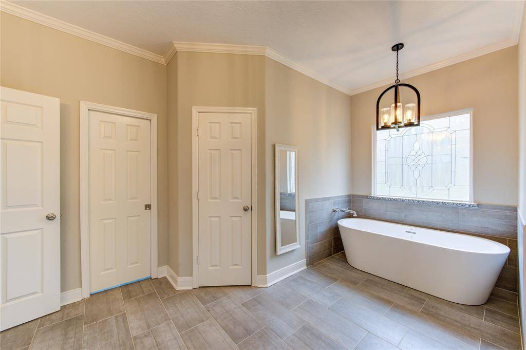 Pictured here are the doors to two separate walk-in closets, offering both ample storage and personalized organization within the primary suite. Whether you're starting your day with an invigorating shower or unwinding in a tranquil bath, this exquisite ensuite offers the ultimate in comfort and refinement. Pictured