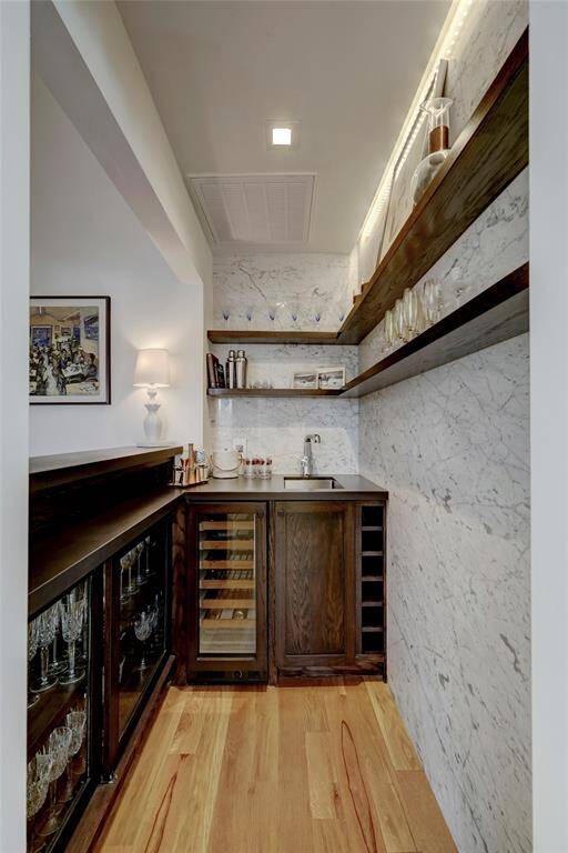 The Wet Bar feels luxurious with Carrara marble walls, custom built wood cabinetry and shelving plus a Sub-Zero Wine Cooler.