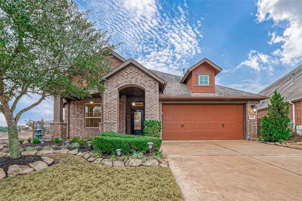 Welcome to Meridiana! This charming David Weekley built home features a brick exterior with a covered entryway. It has a two-car garage and well-maintained landscaping, including a tree and shrubs. The driveway offers ample parking space, and the overall curb appeal is inviting.
