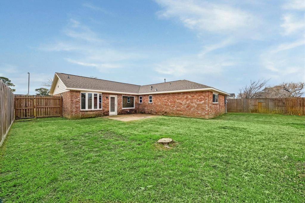 This photo showcases a spacious fenced backyard, featuring a patio area perfect for outdoor activities. The lawn is well-maintained, offering ample space for gardening or recreation.