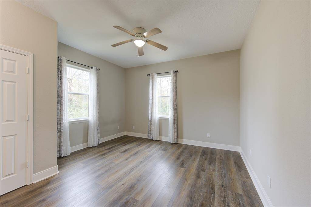Bedroom number 2, located upstairs, is a bright and inviting space, filled with great natural light streaming through the windows that enhance its airy feel.  The view from this room showcases the heavily wooded backyard, offering a peaceful and picturesque retreat.