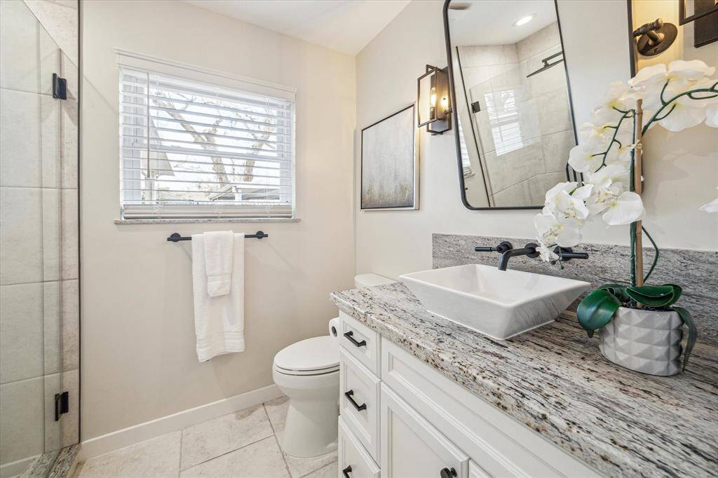This beautifully updated ensuite bathroom features a single sink vanity with a vessel sink, custom mirror and vanity lights.