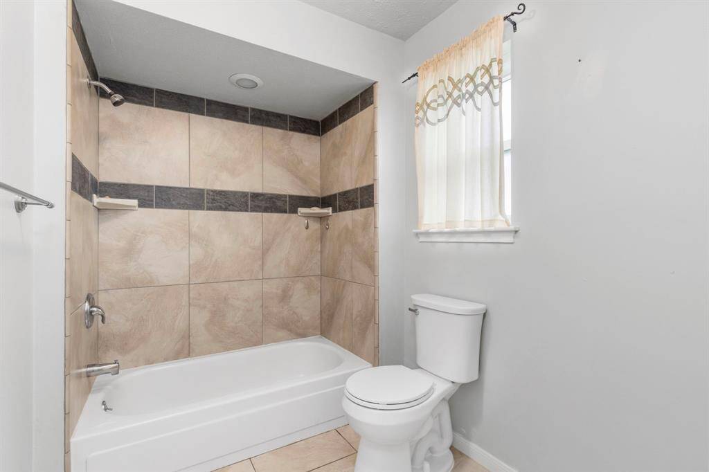 Primary bath with tub/shower combo, tile surround and plenty of extra space for a cute cabinet in the corner.