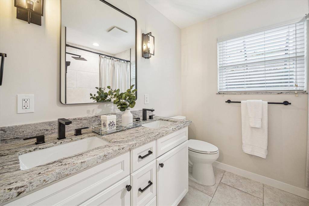 Beautifully updated and easy to share, the guest bathroom features an extended dual sink vanity with upgraded fixtures, sleek lighting and a custom mirror above.