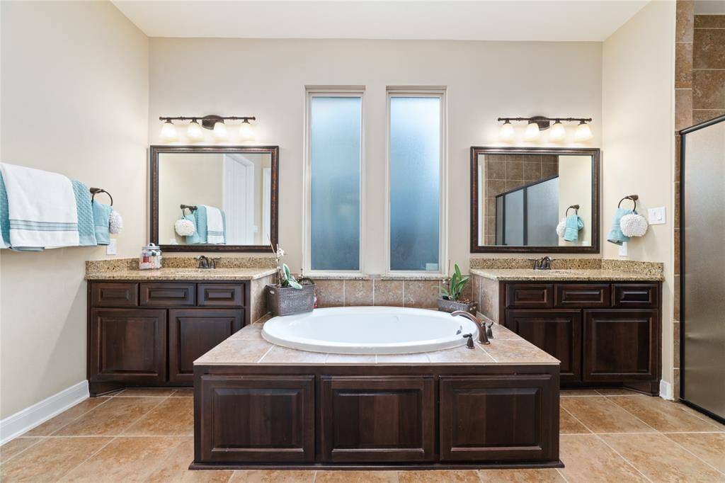 Dual sinks with granite countertops and wood-wrapped tub