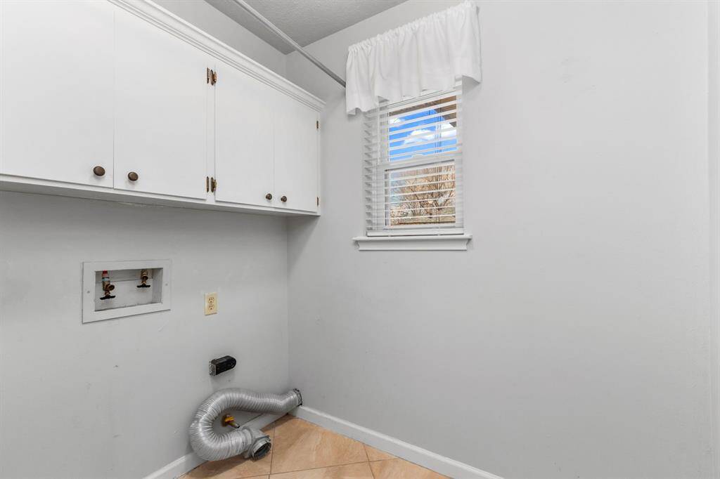 This laundry room is bigger than that wizard-kid's bedroom and has cabinet storage and a window.