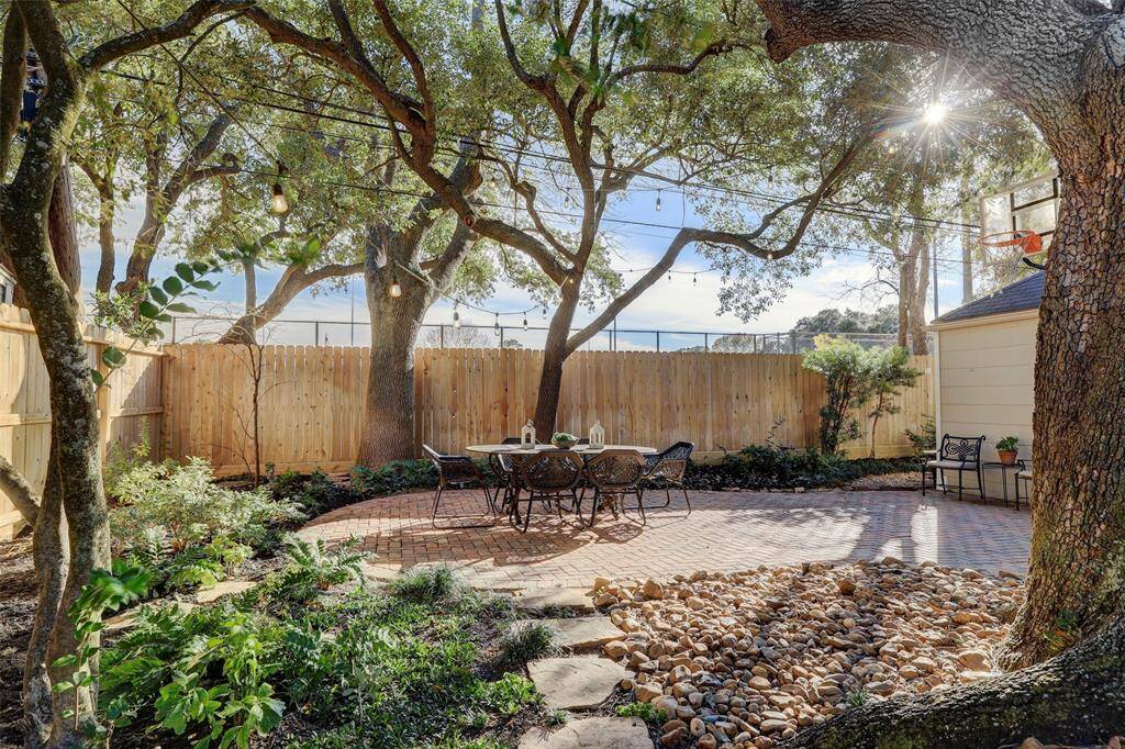 Theres a "charming courtyard" feel to this backyard with its pavers, Live Oaks and party lights.  The back fence was replaced in 2021.