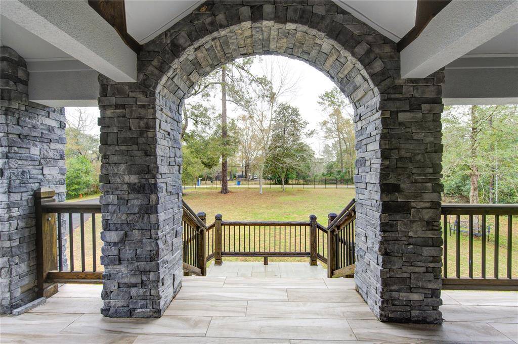 A magnificent stone archway stands as a grand architectural statement, gracefully framing a picturesque view that stretches beyond this beautiful heavility wooded lot.
