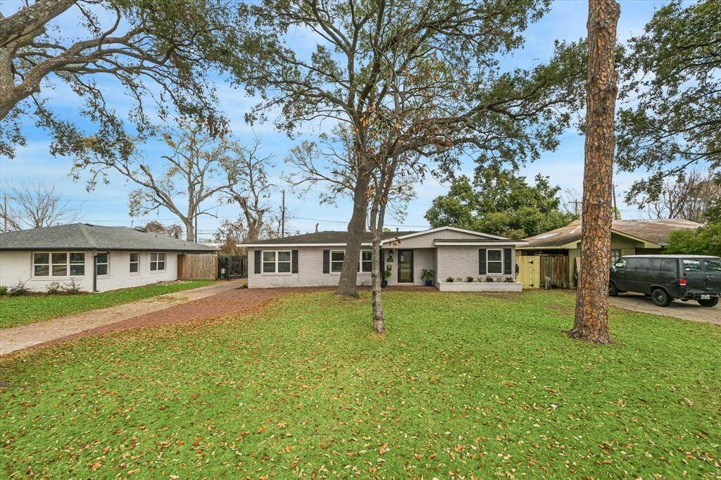 The traditional brick elevation, covered porch with stylish lighting, expansive yard, and towering trees provide a warm welcome home.