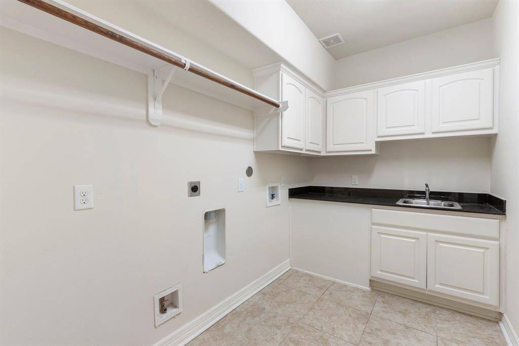Large utility room boasting a rinsing sink + extra counter space for folding/sorting, enclosed cabinet storage and space to hang dry clothes.