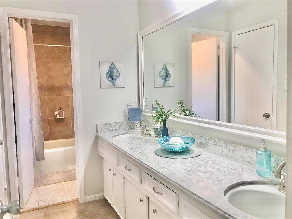View of the hall bath with double sinks & separate tub & toilet room.