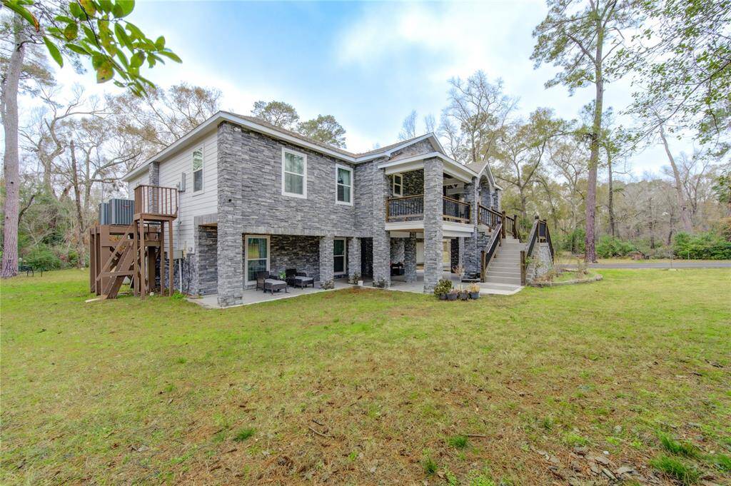 A closer view of the front elevation reveals the home's grand gray stone exterior, exuding both elegance and strength. The covered patio areas provide both function and beauty, offering welcoming outdoor spaces perfect for relaxation or entertaining.