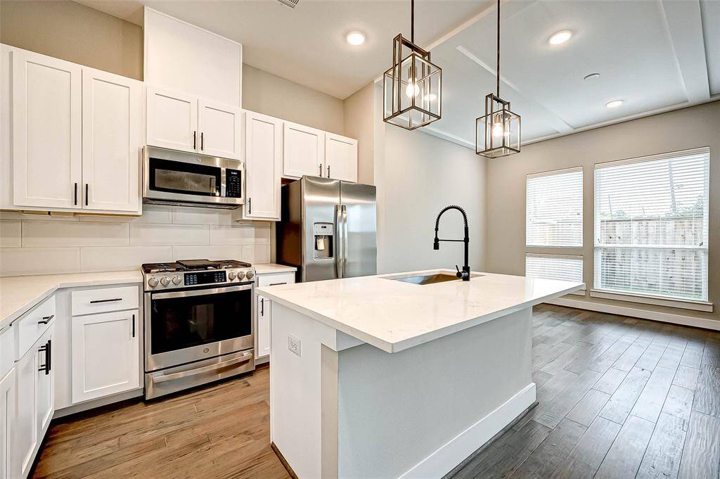 The kitchen has a stainless steel GE Profile appliance package - including dishwasher, microwave, gas range, and side-by-side refrigerator.