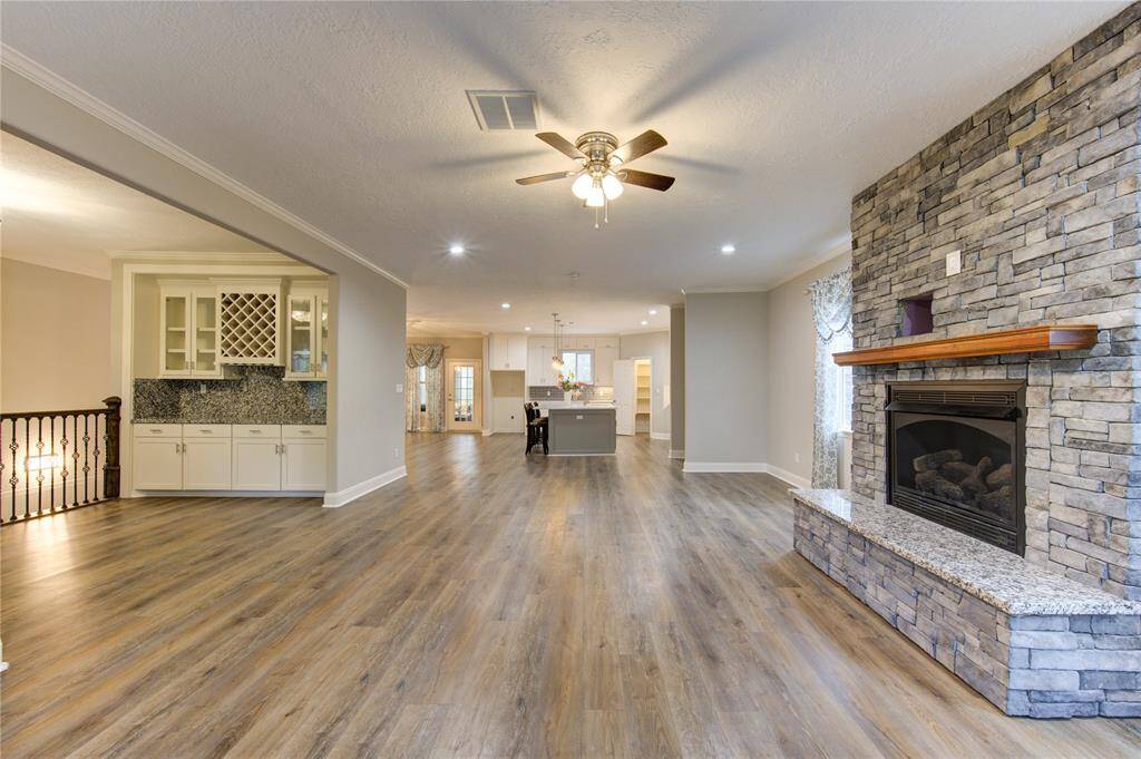 The wine bar seamlessly transitions into the living room, where a regal fireplace serves as the grand focal point, radiating warmth and elegance. Designed for both relaxation and entertaining, this space boasts an open-concept layout, effortlessly connecting to the gourmet kitchen.