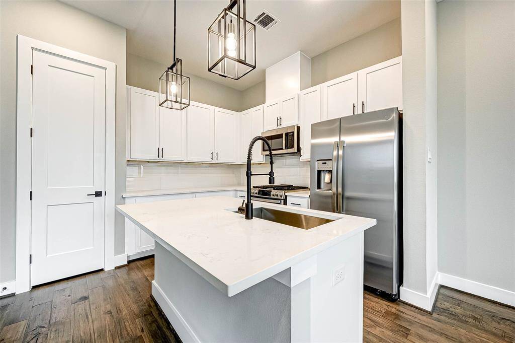 The kitchen has quartz counters, a large undermount sink, island with breakfast bar, and custom pendant lighting.