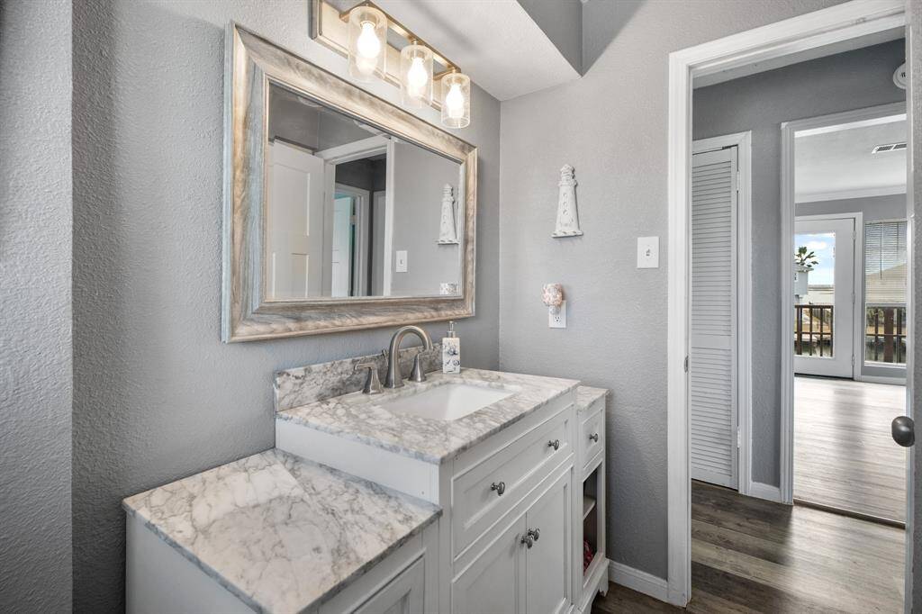 The bathroom features a sleek, modern design with a white granite countertop and vanity, complemented by a large, stylish mirror and contemporary lighting.
