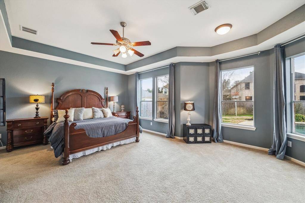 Huge main floor primary bedroom with lots of room for large furniture including a California King-size bed, a wall of windows looking into the backyard and pool.
