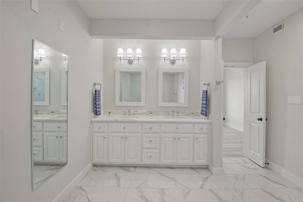 Close up of this wonderful vanity with double sinks and mirrors, polished chrome Kohler faucets and overhead sconce lighting. Notice the storage!