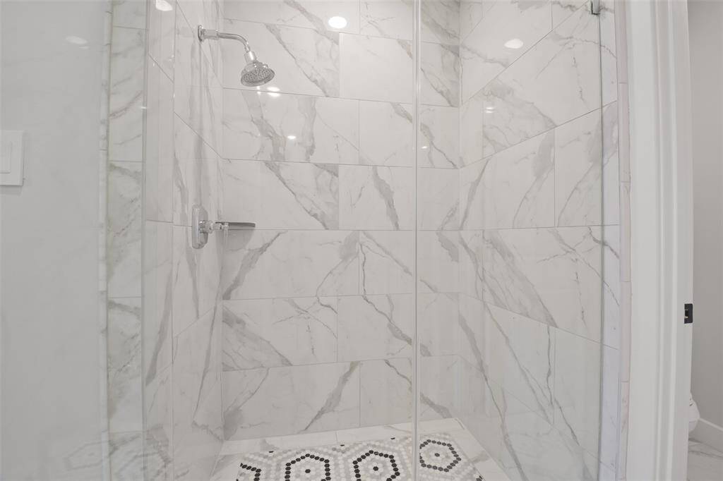 Stunning mosaic tiles accentuate this Owners Suite shower with floor to ceiling tile and polished chrome Kohler showerhead.