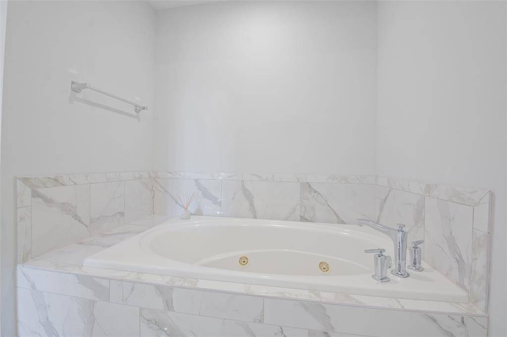 Owners Suite jetted tub with tile surround and Kohler polished chrome faucet and towel rail.