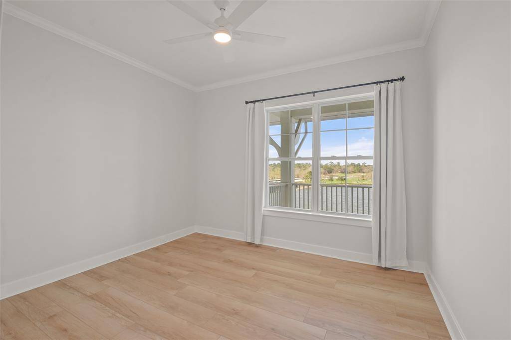This secondary bedroom, located on the north side of the condo, has a window with linen curtains looking out to the lake, LVT flooring and a large closet.