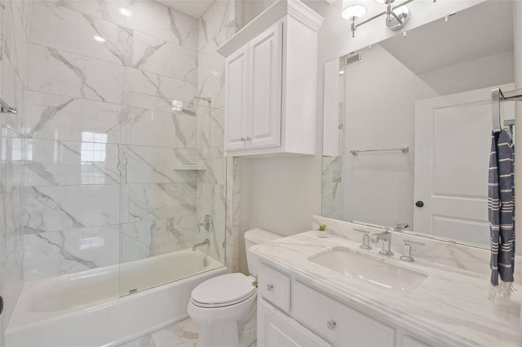 Guest bathroom featuring a custom tiled tub and shower combo with ledge for storage and a Kohler polished chrome shower head and towel bar.