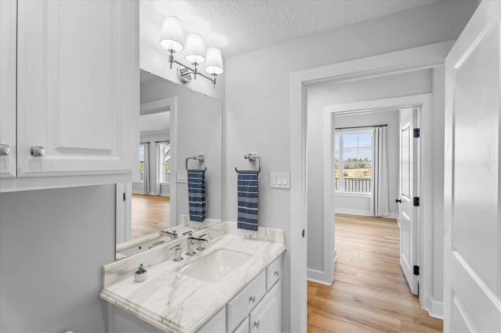 This vanity in the guest bathroom, offers a marble countertop with Kohler sink, overhead sconce chrome lighting, a Kohler polished chrome faucet and towel ring.
